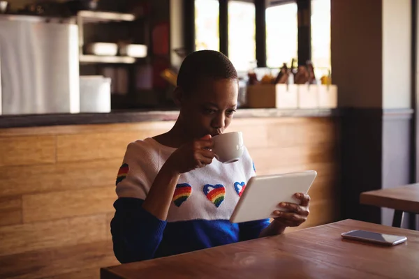 Mulher usando tablet digital enquanto bebe café — Fotografia de Stock