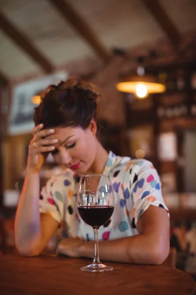 Upset woman sitting with hands on forehead — Stock Photo, Image