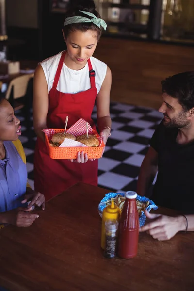 Serveerster serveren hamburger en frietjes aan klant — Stockfoto