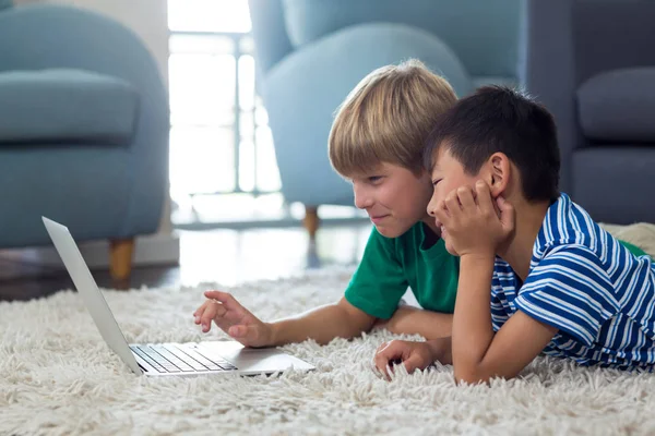 Syskonen liggande på matta och använder bärbar dator — Stockfoto