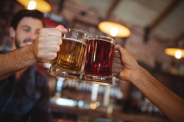 Dois jovens a brindar às canecas de cerveja — Fotografia de Stock