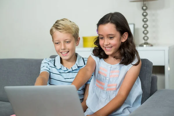 Geschwister nutzen Laptop im Wohnzimmer — Stockfoto