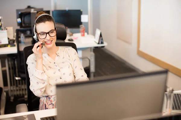 Mujer de negocios usando auriculares en la oficina — Foto de Stock