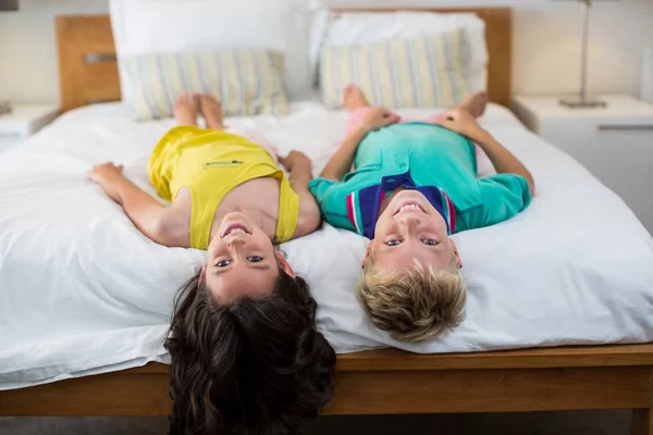 Lächelnde Geschwister liegen im Schlafzimmer auf dem Bett — Stockfoto