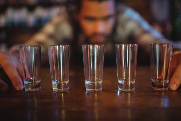 Waiter placing shot glasses on counter — Stock Photo, Image