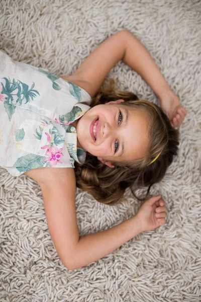 Menina deitada no tapete na sala de estar — Fotografia de Stock