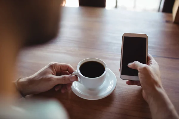 Mann benutzt Handy beim Kaffeetrinken — Stockfoto