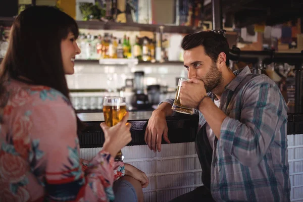 カウンターでビールを飲みながら対話するカップル — ストック写真