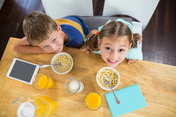 Siblings having breakfast cereal in kitchen — Stock Photo, Image