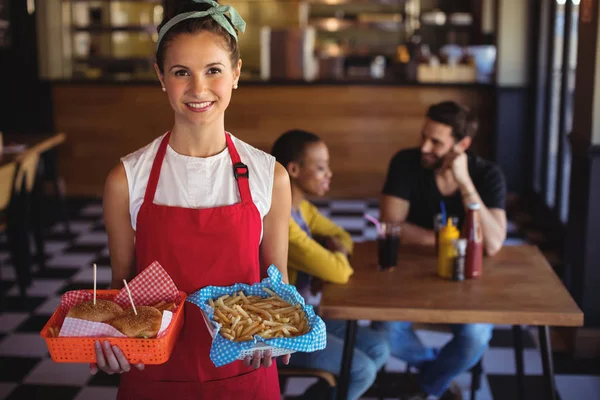 Servírka drží burger a hranolky v zásobníku — Stock fotografie