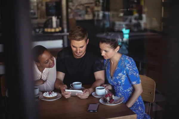 Amigos usando tablet digital enquanto tomam café da manhã — Fotografia de Stock