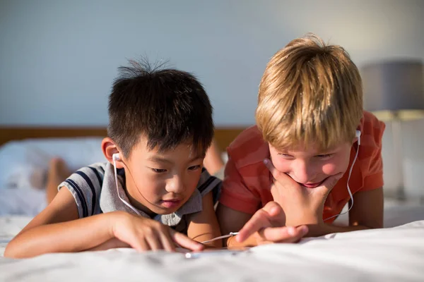 Hermanos escuchando música mientras usan el teléfono —  Fotos de Stock