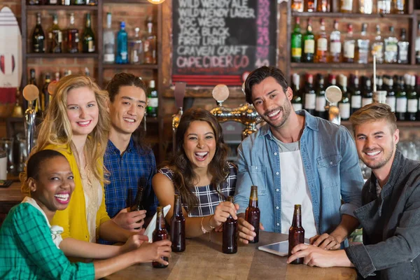 Amigos alegres com garrafas de cerveja no pub — Fotografia de Stock