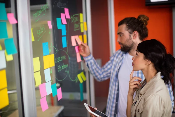 Male and female executives looking at sticky notes — Stock Photo, Image