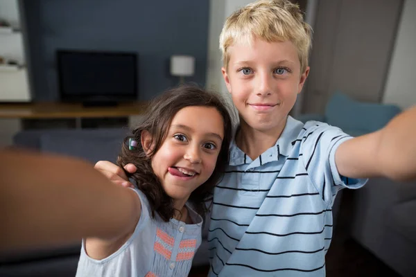Hermanos tomando selfie en sala de estar —  Fotos de Stock