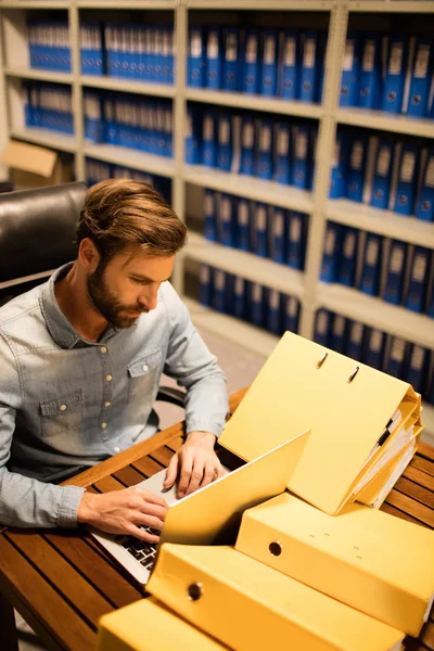 Affärsman med laptop på tabellen i filen förråd — Stockfoto