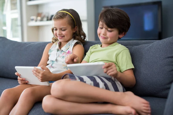 Siblings using digital tablet in living room — Stock Photo, Image