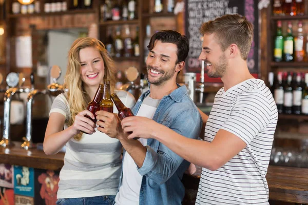Amigos brindam com garrafas de cerveja no pub — Fotografia de Stock