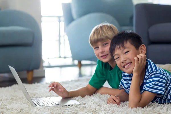 Frères et sœurs couchés sur un tapis et utilisant un ordinateur portable — Photo