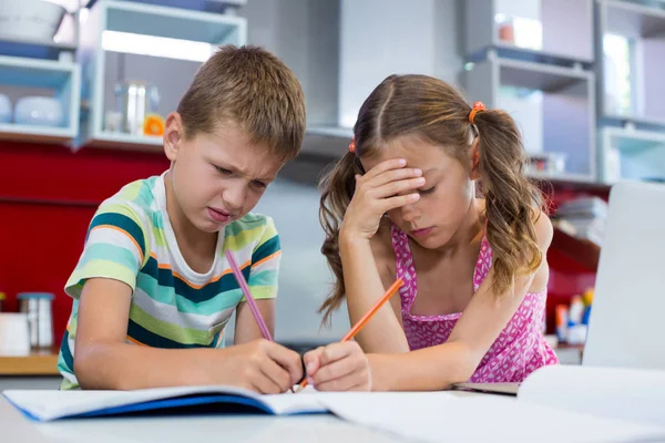 Tense siblings doing homework in kitchen — Stock Photo, Image