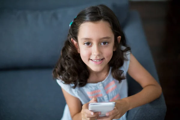 Girl sitting on sofa and using phone — Stock Photo, Image