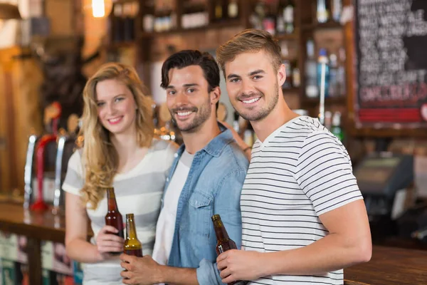 Vrienden houden bierflesjes in pub — Stockfoto