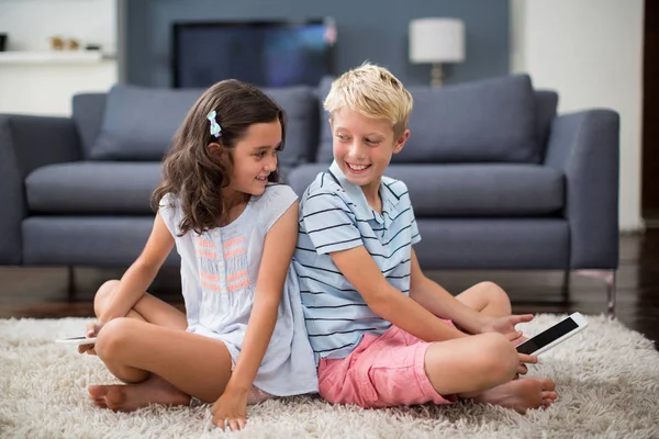 Broers en zussen zitten op tapijt en het gebruik van Tablet PC — Stockfoto