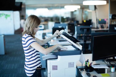 businesswoman using copy machine in office clipart