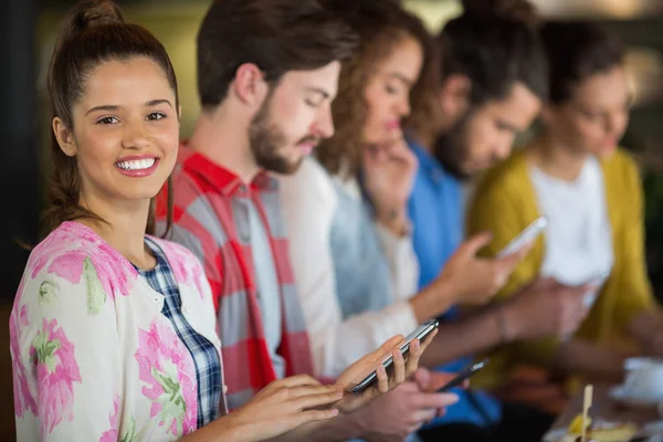 Woman holding mobile phone while sitting with friends — Stock Photo, Image