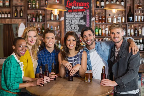 Amigos com cervejas à mesa no pub — Fotografia de Stock