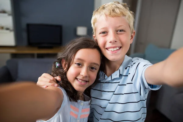 Søskende tager selfie i stuen - Stock-foto