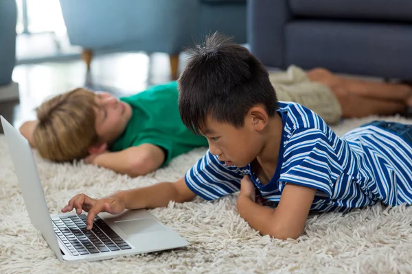 Fiú feküdt szőnyeg és használ laptop — Stock Fotó