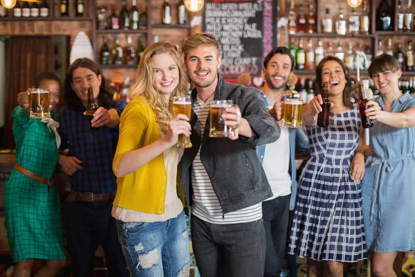 Amigos alegres segurando copos de cerveja no pub — Fotografia de Stock