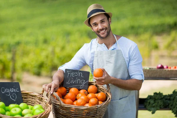 Man standing by fresh fruits in wicker basket — Stock Photo, Image