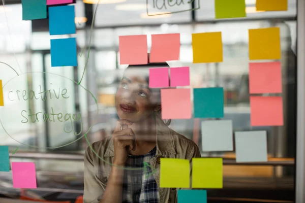 Female executive looking at sticky notes — Stock Photo, Image