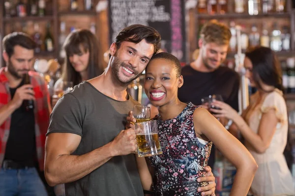 Couple embracing while holding beer mugs — Stock Photo, Image