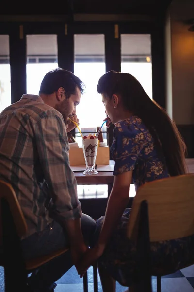 Couple holding hands while having milkshake — Stock Photo, Image