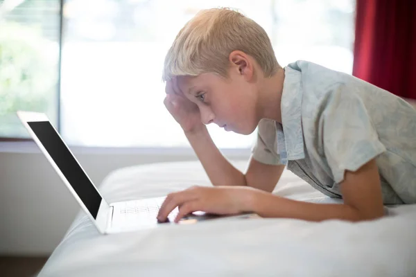 Menino tenso usando laptop na cama no quarto — Fotografia de Stock