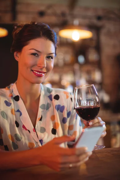 Vrouw met behulp van mobiele telefoon terwijl het hebben van wijn — Stockfoto