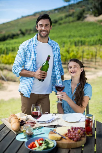 Coppia che tiene bottiglia di vino rosso e vetro — Foto Stock