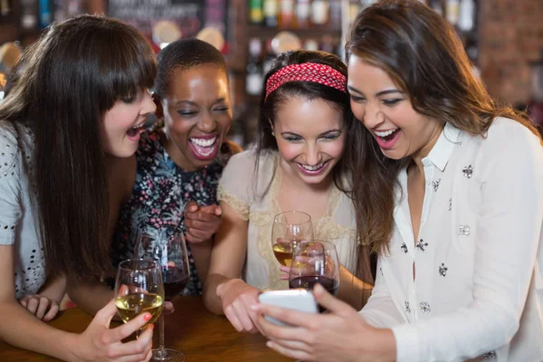 Подруги с винными бокалами с помощью мобильного телефона — стоковое фото