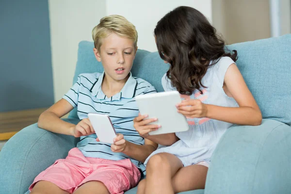 Siblings using tablet and phone — Stock Photo, Image
