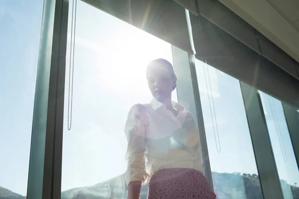 Femme d'affaires debout près de la fenêtre brillamment éclairée — Photo