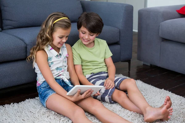 Broers en zussen met behulp van digitale tablet in woonkamer — Stockfoto