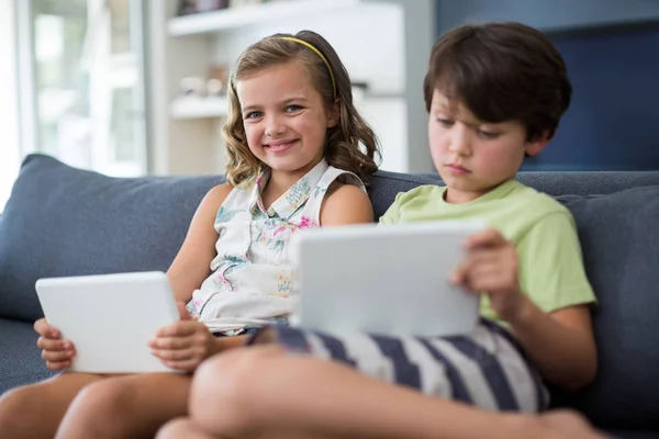 Sourozenci pomocí digitálních tabletu v obývacím pokoji — Stock fotografie