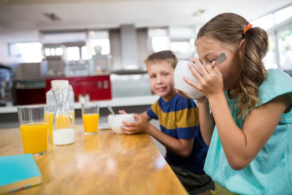 Syskon med frukostflingor i kök — Stockfoto