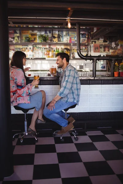 Casal interagindo enquanto toma cerveja no balcão — Fotografia de Stock