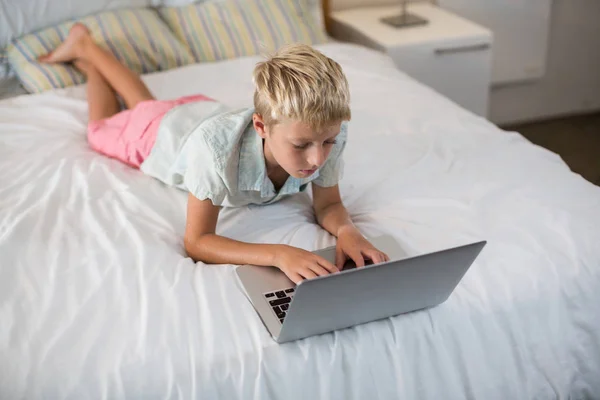 Хлопчик використовує ноутбук на ліжку в спальні — стокове фото