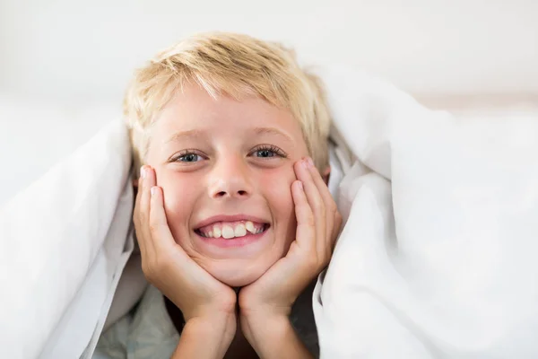 Jongen liggend onder bed blad in slaapkamer — Stockfoto