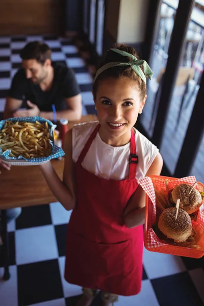 Офіціантка тримає бургер і картоплю фрі в лотку — стокове фото